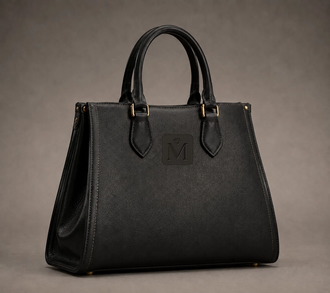 Matte black leather tote bag with rolled twin handles and embossed monogram